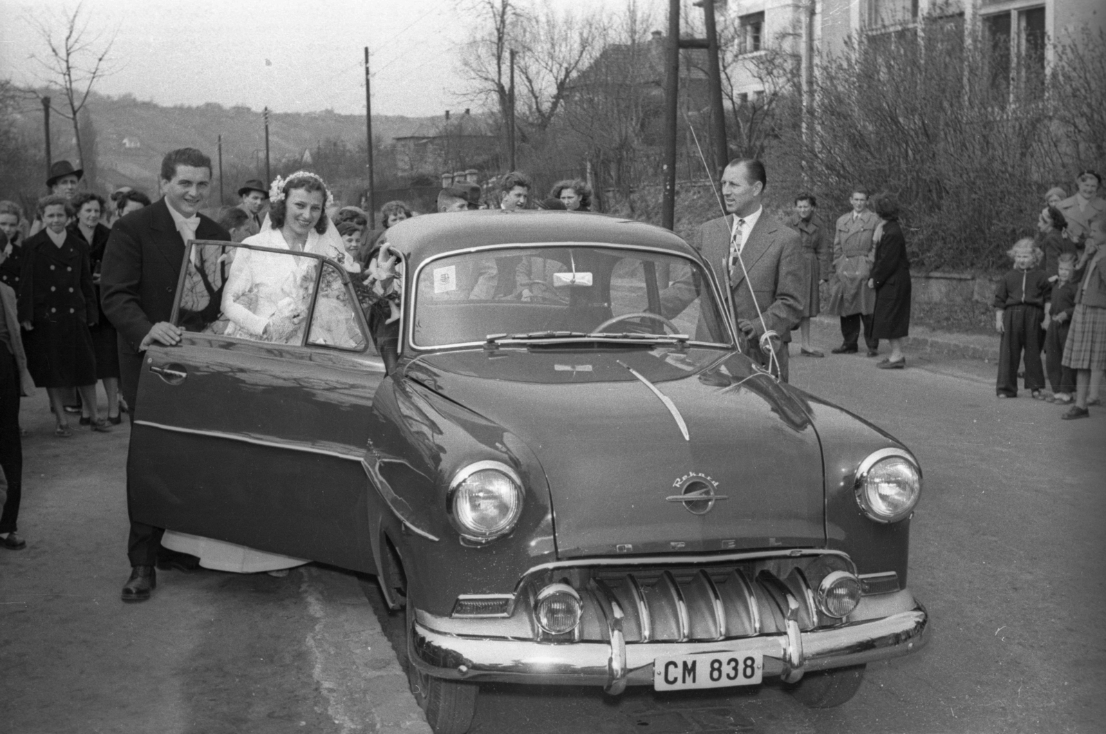 Magyarország, Budapest II., Máriaremetei (Dimitrov) út a Remetekertvárosi Szentlélek templom előtt. Távolban a Hosszú-erdő-hegy látszik., 1957, Hámori Gyula, Opel-márka, menyasszony, vőlegény, Budapest, Opel Olympia 1955, rendszám, Fortepan #123751