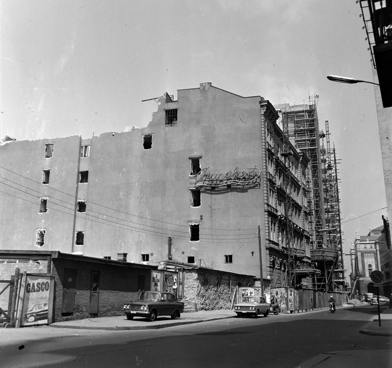 Magyarország, Budapest V., Apáczai Csere János utca, a Duna szálloda bontása, az épület előkészítve a robbantásra. Háttérben az épülő Hotel Duna Intercontinental és a Vigadó a Régi posta utca sarkától nézve., 1969, Bauer Sándor, Budapest, Fortepan #126663