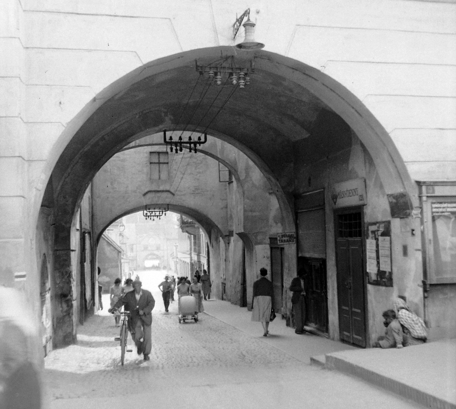 Slovakia, Prešov, Fő utca, az egykori Városháza (később Bormúzeum) átjárója., 1956, Gyöngyi, Czechoslovakia, bicycle, light, baby carriage, aerial wire, tobacco shop, store display, passage, gateway, Fortepan #12702
