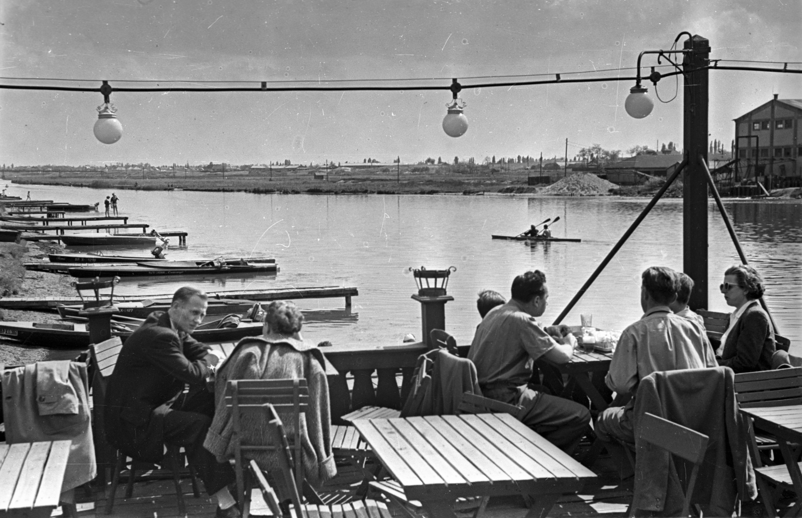 Magyarország, Budapest XX.,Budapest XXI., a Ráckevei (Soroksári)-Duna partján az Erzsébet Strand alatti vendéglő terasza. A túlparton a Csepeli Papírgyár épülete látható., 1957, Bauer Sándor, Budapest, asztal, beszélgetés, folyópart, Fortepan #127907