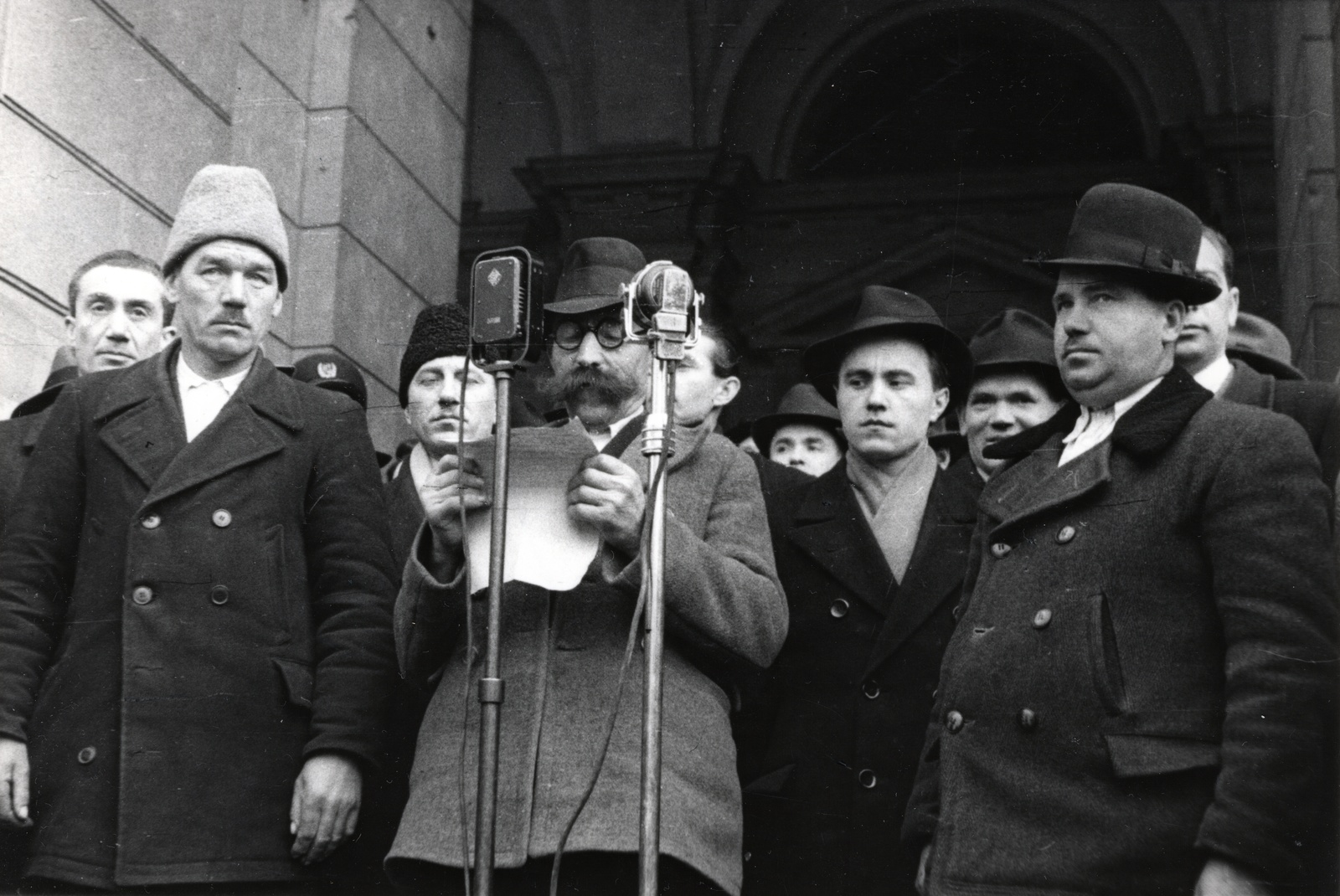 Hungary, Budapest V., Kossuth Lajos tér, a felvétel a Földművelésügyi Minisztérium bejárata előtt készült. Mezőgazdasági gépek átvételére érkezett földművesek propagandabeszédet tartanak 1948. március 1-én., 1948, Bauer Sándor, moustache, microphone, speech, Budapest, reading, hat, Fortepan #128516