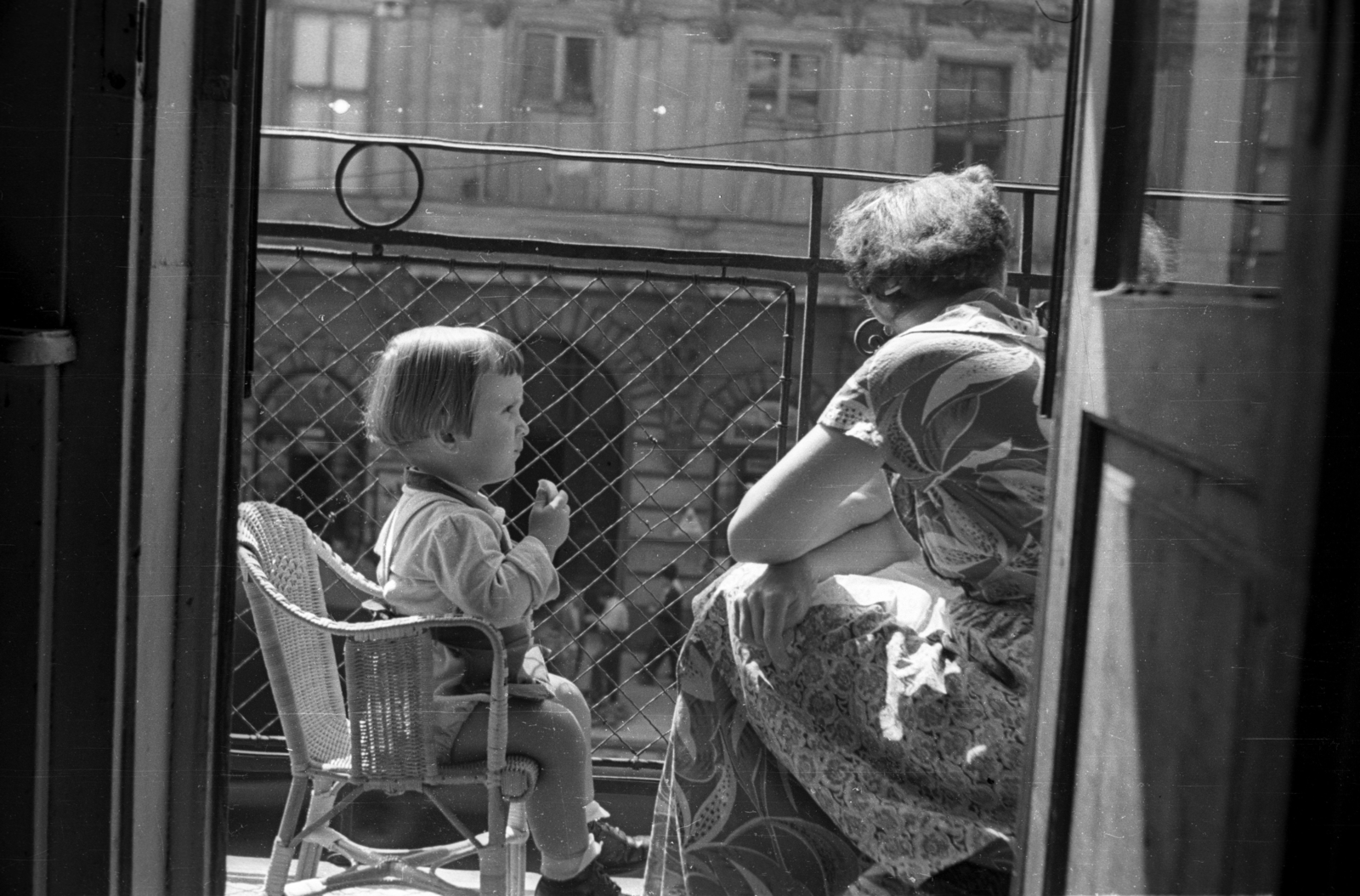 Hungary, Budapest V., a Kossuth Lajos utca a 6-os számú ház első emeleti erkélye., 1955, Horváth Miklós dr, Budapest, girl, balcony, mother, wicker chair, sunshine, railing, summer dresses, Fortepan #129347