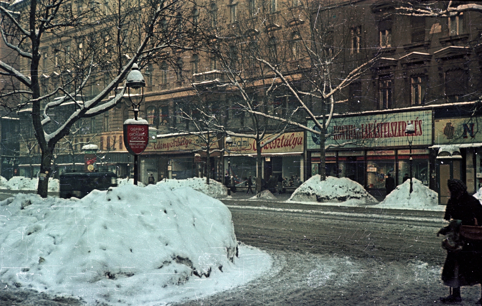 Hungary, Budapest VIII.,Budapest VII., Rákóczi út a Vas utca felől a Kazinczy utca felé nézve., 1952, Horváth Miklós dr, Budapest, street view, sign-board, colorful, snow, snow piles, Fortepan #129552