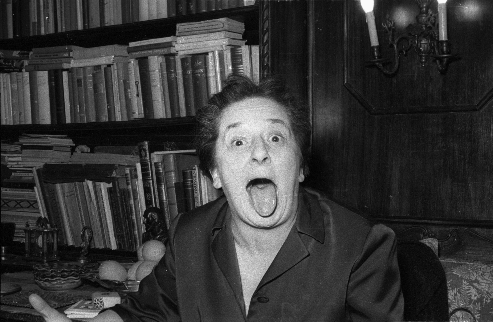 Hungary, Budapest II., Orsó utca 41., Gobbi Hilda színművésznő az otthonában., 1965, Hunyady József, grimace, Budapest, bookshelf, sticking tongue out, Fortepan #129642