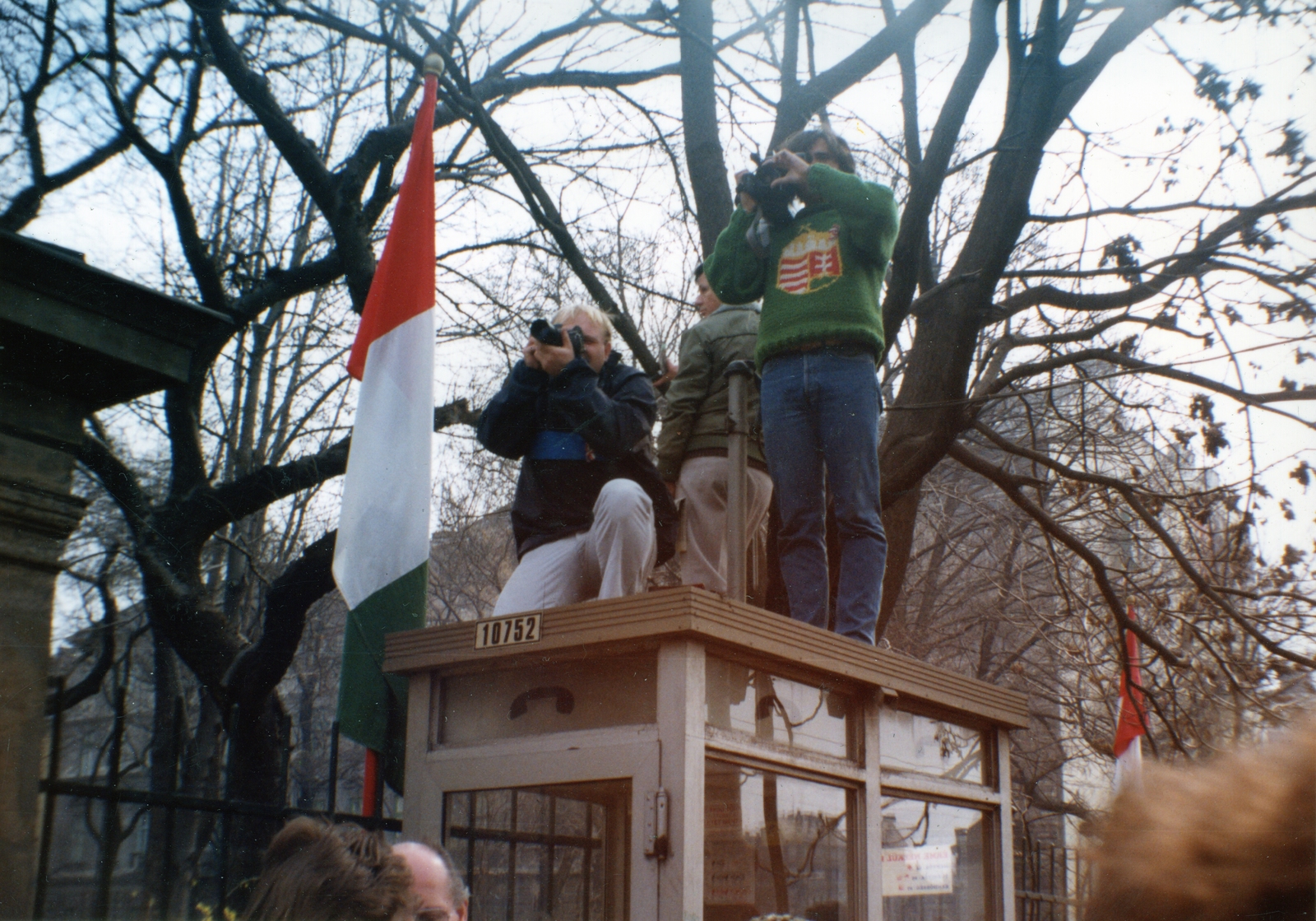 Hungary, Budapest VIII., Múzeum körút a Magyar Nemzeti Múzeum bejáratától a Múzeum utca felé nézve. A fotósok múzeumkerti március 15-i ünnepség résztvevőit fényképezik a telefonfülke tetejéről., 1989, Marics Zoltán, colorful, phone booth, strike, Budapest, press photographer, clever, crest, Fortepan #131443