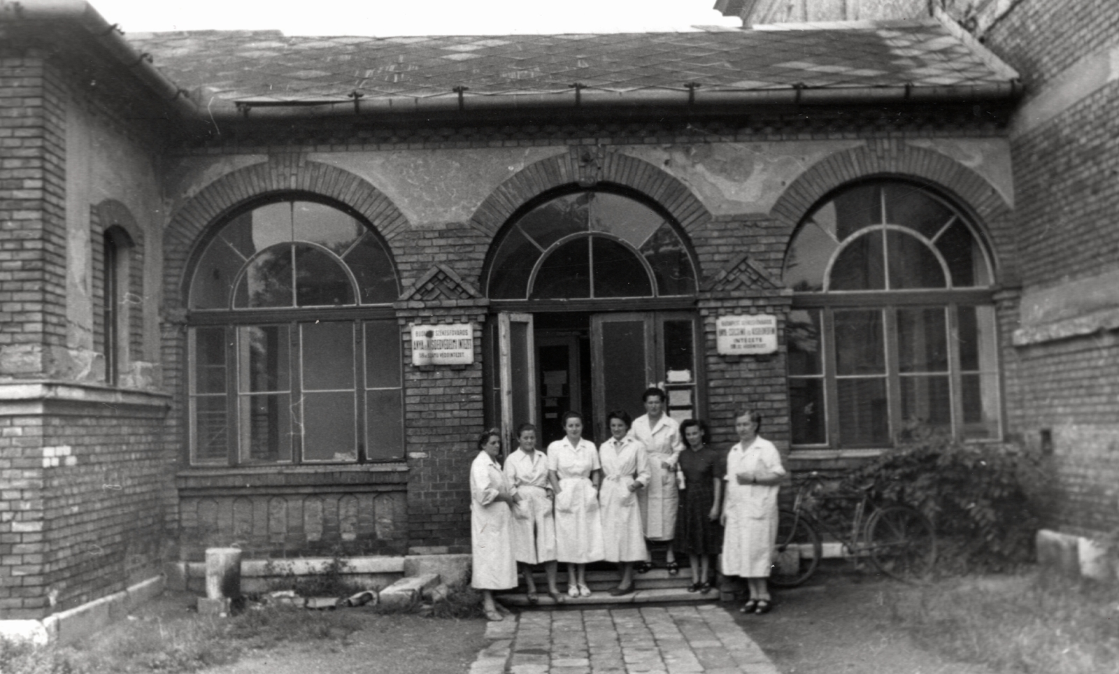 Hungary, Budapest XIV., Álmos vezér tér 10., Anya- és Csecsemővédelmi Intézet 18. számú védőintézete., 1954, Samodai József Zuglói Helytörténeti Műhely, bicycle, Budapest, overall, women, brick covering, enamel sign, healthcare, baby bottle, Fortepan #131954