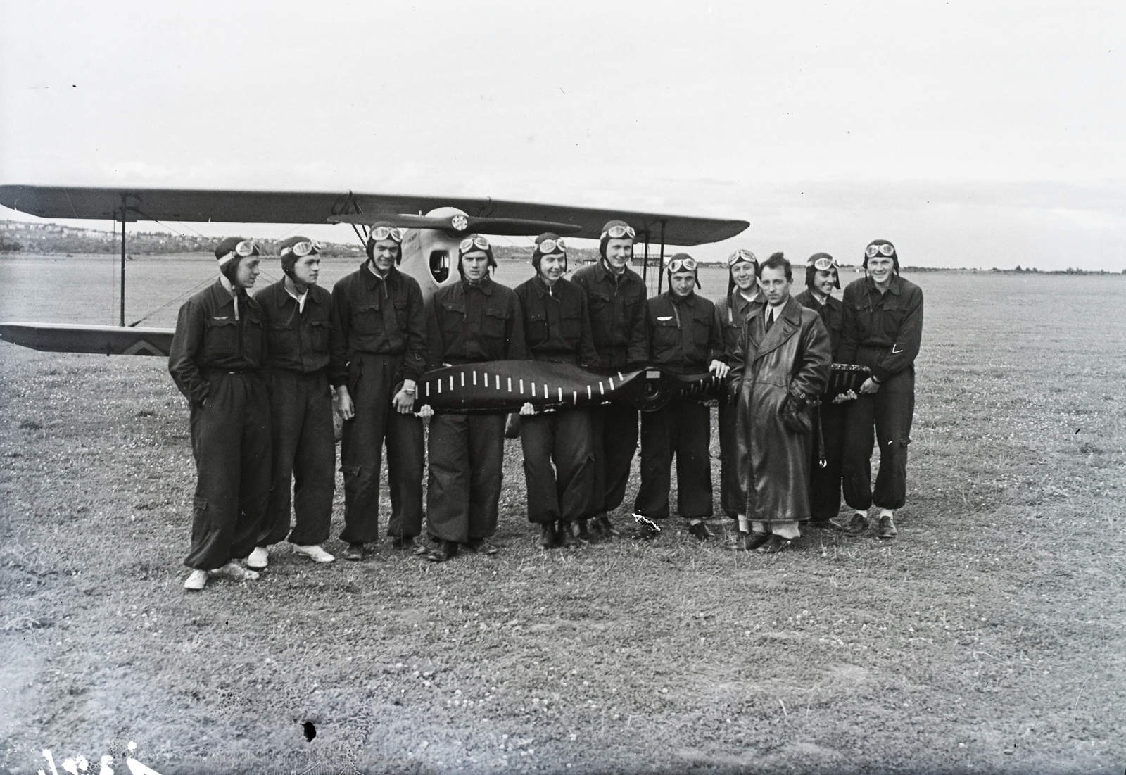 Hungary, Budaörs Airport, Budapest XI., a Horthy Miklós Nemzeti Repülő Alap kiképző kerete kezükben »a büntető légcsavarral«, bőrkabátban oktatójuk Czillei Géza. Háttérben iskolarepülőgépük, Bücker Bü 131 "Jungmann" repülőgép. Leltári jelzet: 1374, 1943, Magyar Műszaki és Közlekedési Múzeum / Archívum / Negatívtár / Magyar Nemzeti Múzeum Történeti Képcsarnok gyűjteménye, pilot, airplane, leather jacket, airport, propeller, Budapest, Fortepan #132676