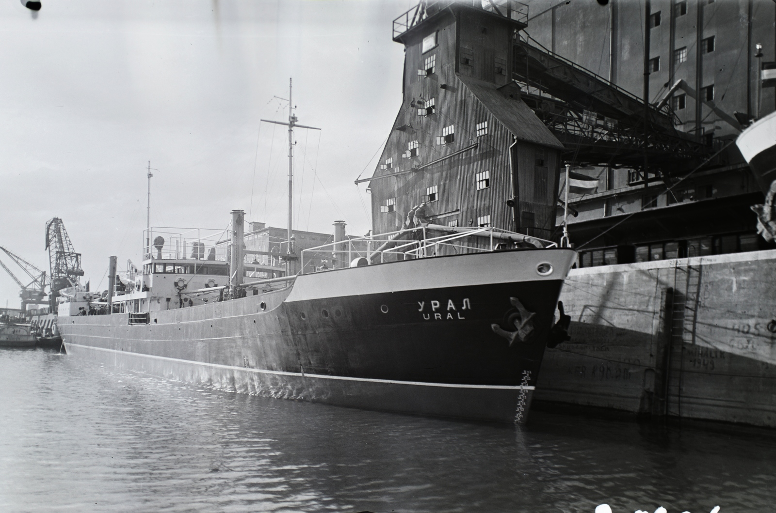 Hungary, Csepeli Szabadkikötő, Budapest XXI., az Óbudai Hajógyárban épült Ural (1949) folyam-tengeri áruszállító csavaros motorhajó a Gabonatárház előtt. Leltári jelzet: 21636, 1949, Magyar Műszaki és Közlekedési Múzeum / Történeti Fényképek Gyűjteménye / Óbudai Hajógyár gyűjteménye, Budapest, Cyrillic alphabet, Fortepan #133094