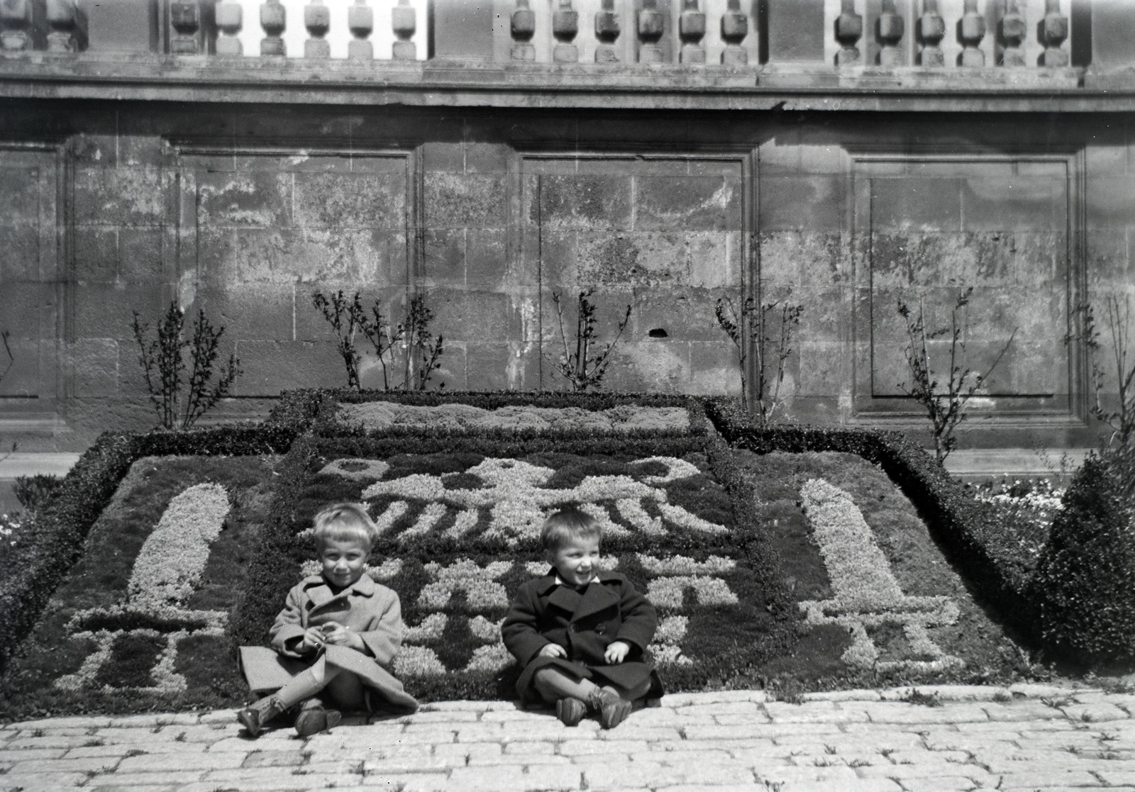 Hungary, Pécs, Dóm (Scitovszky) tér a Szent Péter- és Szent Pál-székesegyház előtt., 1941, Varga Csaba dr., sitting on the ground, crest, flower bed, floral pattern, Fortepan #133570