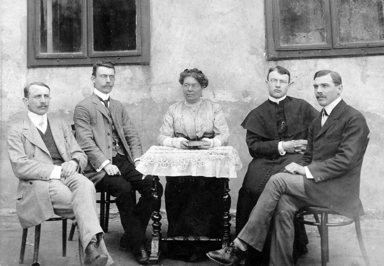 Magyarország, Halászi, Halászi tantestület 1912-ben, balszélen ifj. Timaffy Endre, papi ruhában pedig Timaffy László káplán., 1912, Fortepan, könyv, udvar, pap, csoportkép, férfiak, nő, asztal, reverenda, csipke, Fortepan #13516