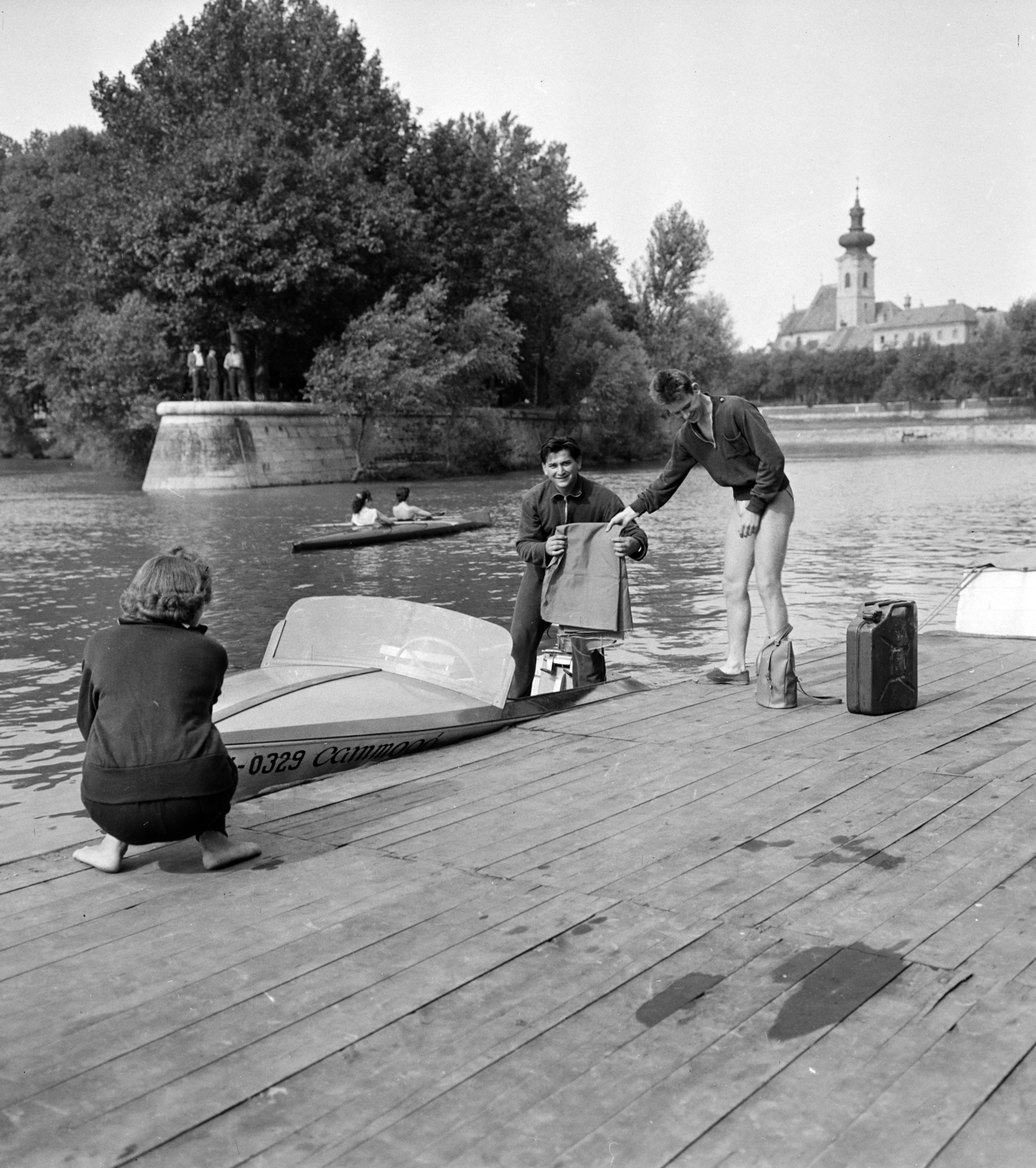 Magyarország, Győr, a Rába, csónakház a Zechmeister utcánál a Petőfi híd felől nézve, balra a Radó-sziget déli csúcsa, jobbra a Karmelita templom., 1959, Szalay Zoltán, templom, barokk-stílus, motorcsónak, guggolás, marmonkanna, Fortepan #137551