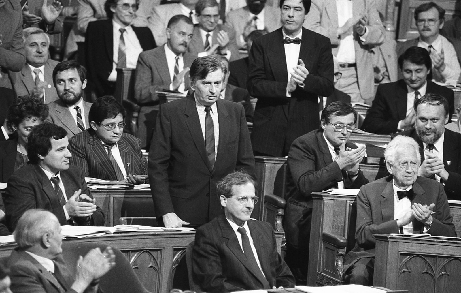 Hungary, Budapest V., Parlament, az Országgyűlés ülése. A felvétel 1990. május 22-én készült, az Antall-kormány kormányprogramjának kihirdetése után. Az első sorban Göncz Árpád, Sólyom László, Szentágothai János ül. Középen áll Antall József miniszterelnök, tőle jobbra Balsai István és Salamon László, mögöttük állva tapsol Csóti György, tőle balra bajusszal Zétényi Zsolt. A jobb felső sarokban Zacsek Gyula., 1990, Szalay Zoltán, celebrity, clapping, prime minister, Budapest, politician, Fortepan #138510