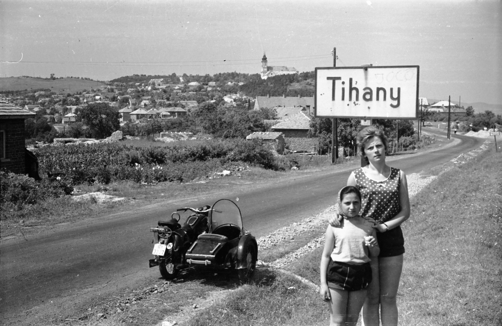 Hungary,Lake Balaton, Tihany, Kossuth Lajos utca a község határában, háttérben a Bencés Apátság., 1960, Morvay Kinga, motorcycle with sidecar, number plate, place-name signs, dotted dress, country code sign, Fortepan #140447