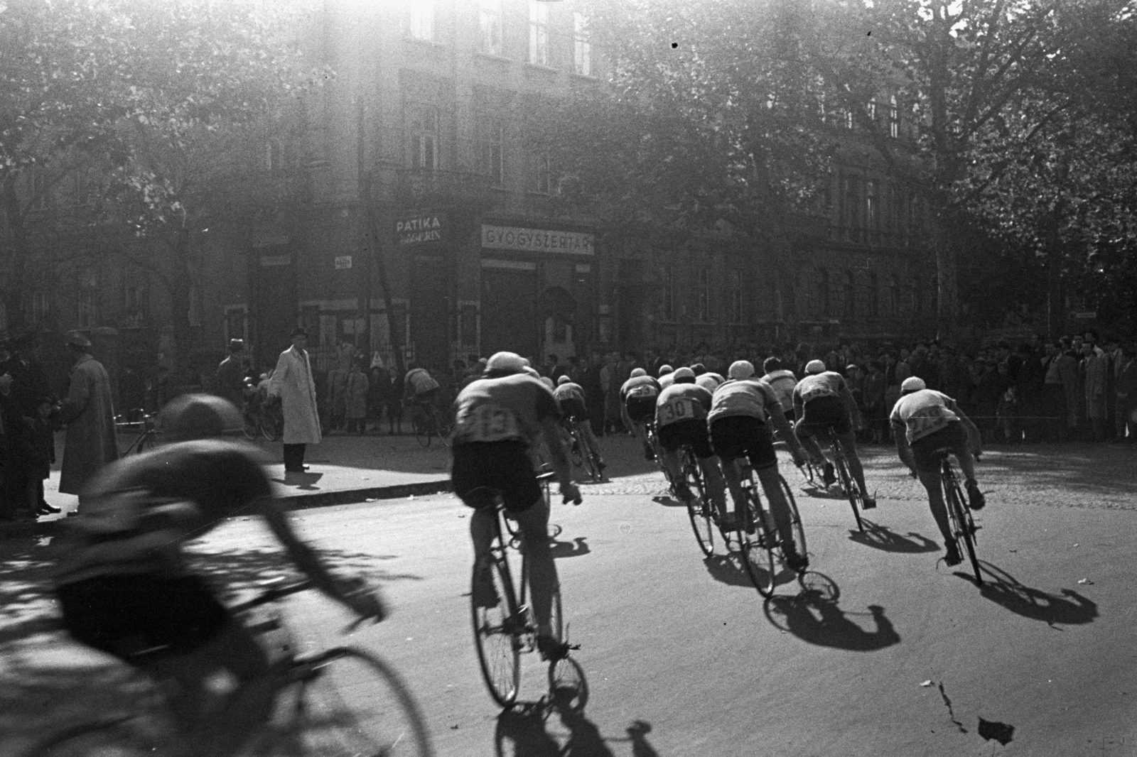 Hungary, Budapest VI., Andrássy út, háttérben a 99. számú épület. A háztömbkörüli kerékpárverseny résztvevői a Hősök tere felől érkezve befordulnak a Bajza utcába., 1948, Chuckyeager tumblr, starting number, Budapest, bicycle race, pharmacy, Fortepan #142747