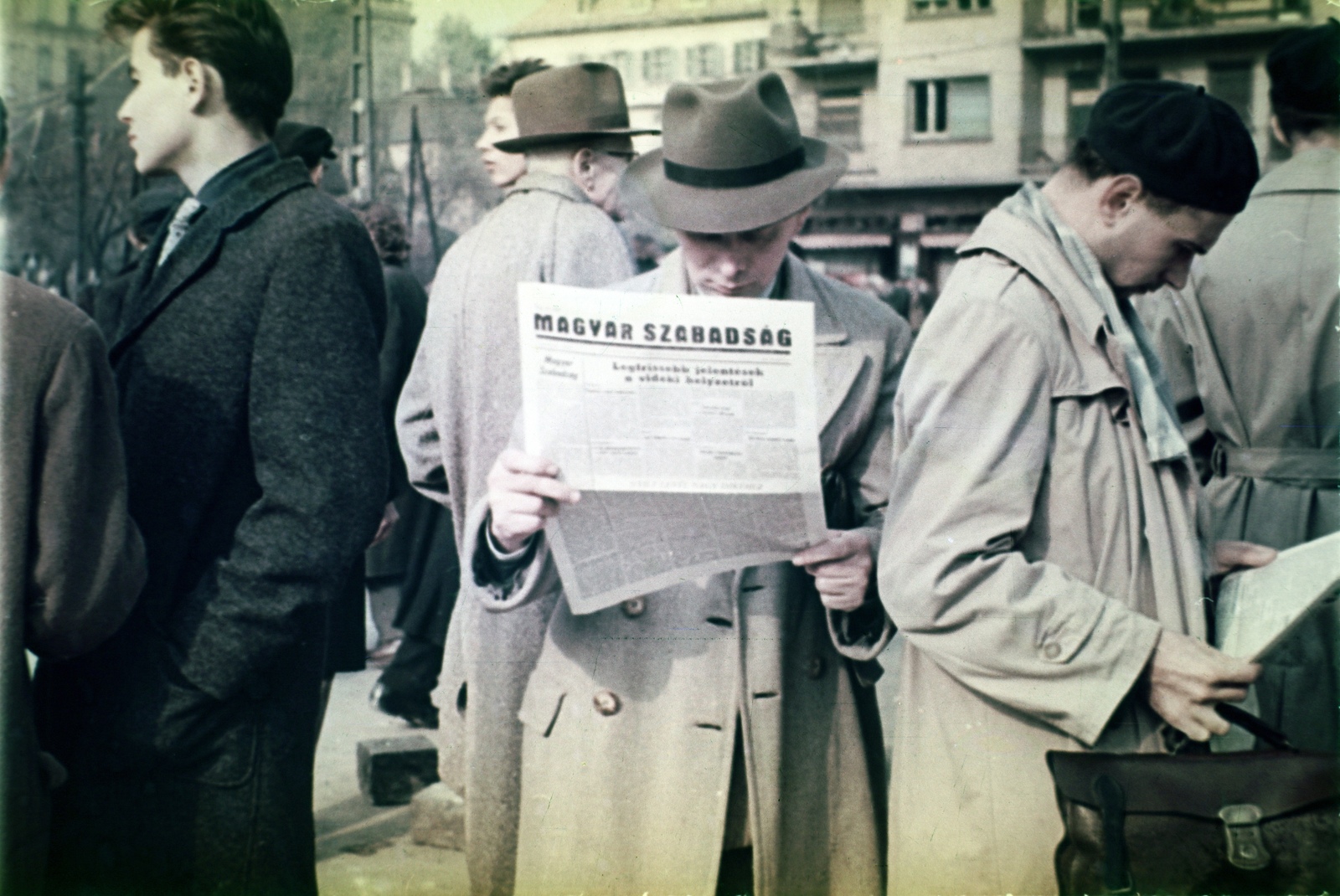 Magyarország, Budapest XI., Móricz Zsigmond körtér a Villányi út torkolatánál. A háttérben balra a Kaffka Margit Gimnázium (később Szent Margit Gimnázium) épülete, jobbra a Himfy utcai saroképület., 1956, Klausz Ádám, kalap, színes, forradalom, olvasás, újság, svájcisapka, Budapest, Magyar Szabadság, Fortepan #146965