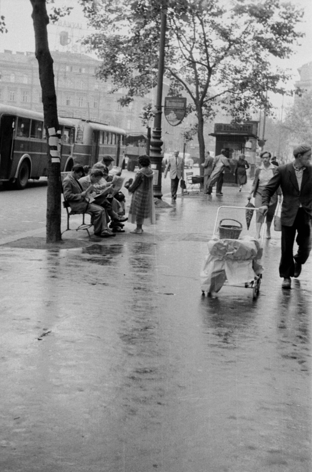 Magyarország, Budapest VI., Teréz (Lenin) körút az Aradi utcától az Oktogon (November 7. tér) felé nézve., 1955, Barbjerik Ferenc, Budapest, kézikocsi, esernyő, olvasás, újság, vesszőkosár, esőkabát, trafik, pad, trolibusz, Fortepan #148374