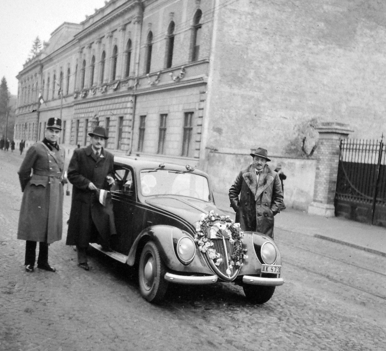 Slovakia, Košice, Csermely utca, az állami felsőbb ipariskola épülete. Fiat 1500A típusú személygépkocsi., 1940, Négyesi Pál, Fiat-brand, high school, Italian brand, automobile, hands behind the back, hands in pockets, Fortepan #14895