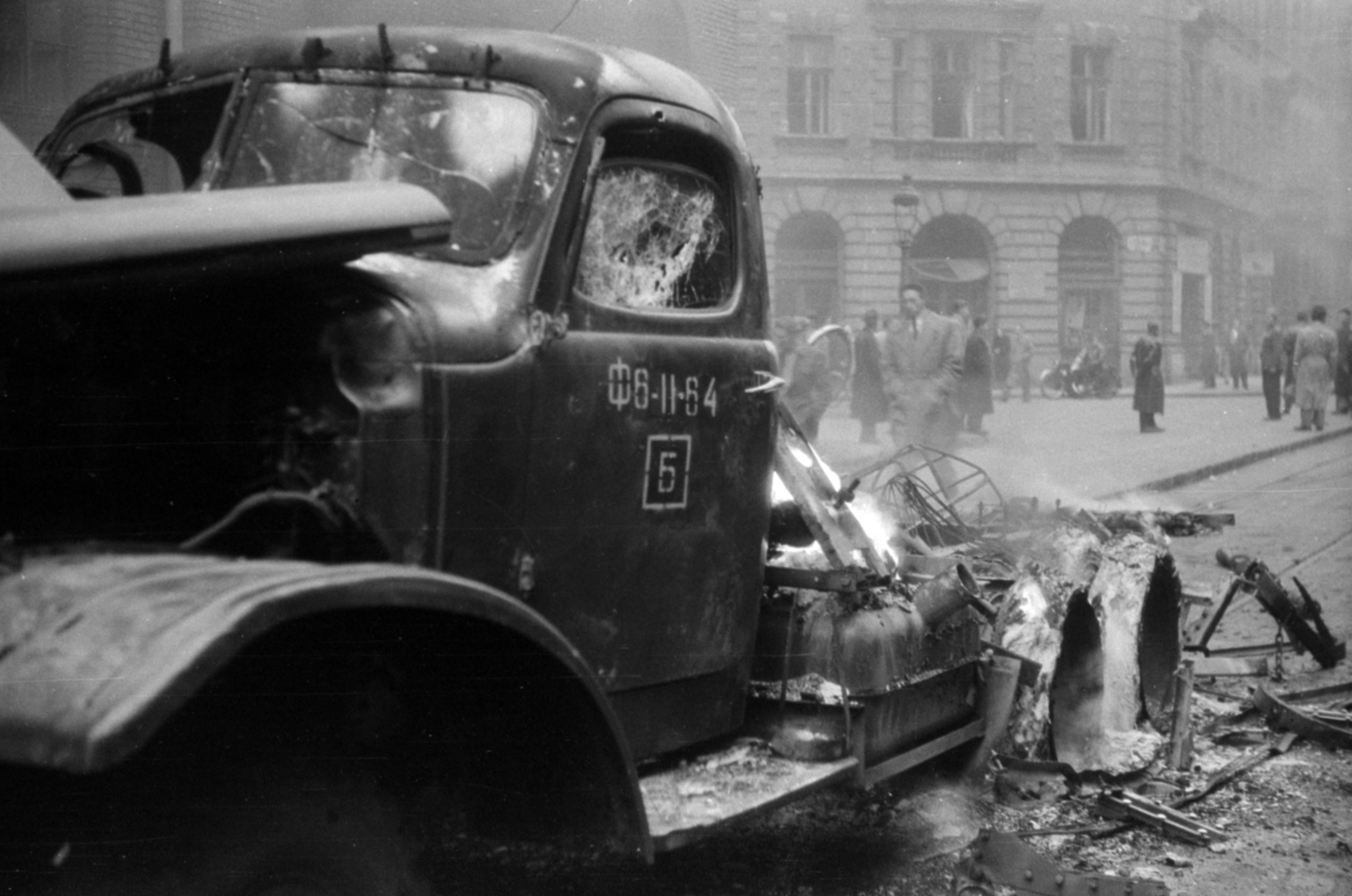 Magyarország, Budapest VIII., Népszínház utca a Bánki Donát Gépipari Középiskola (később főiskola) épülete előtt. Zisz-151 típusú szovjet teherautó roncsa. Háttérben balra a Csokonai utca., 1956, Fortepan/Album027, forradalom, Budapest, láng, járműroncs, Zisz 151, Fortepan #149266