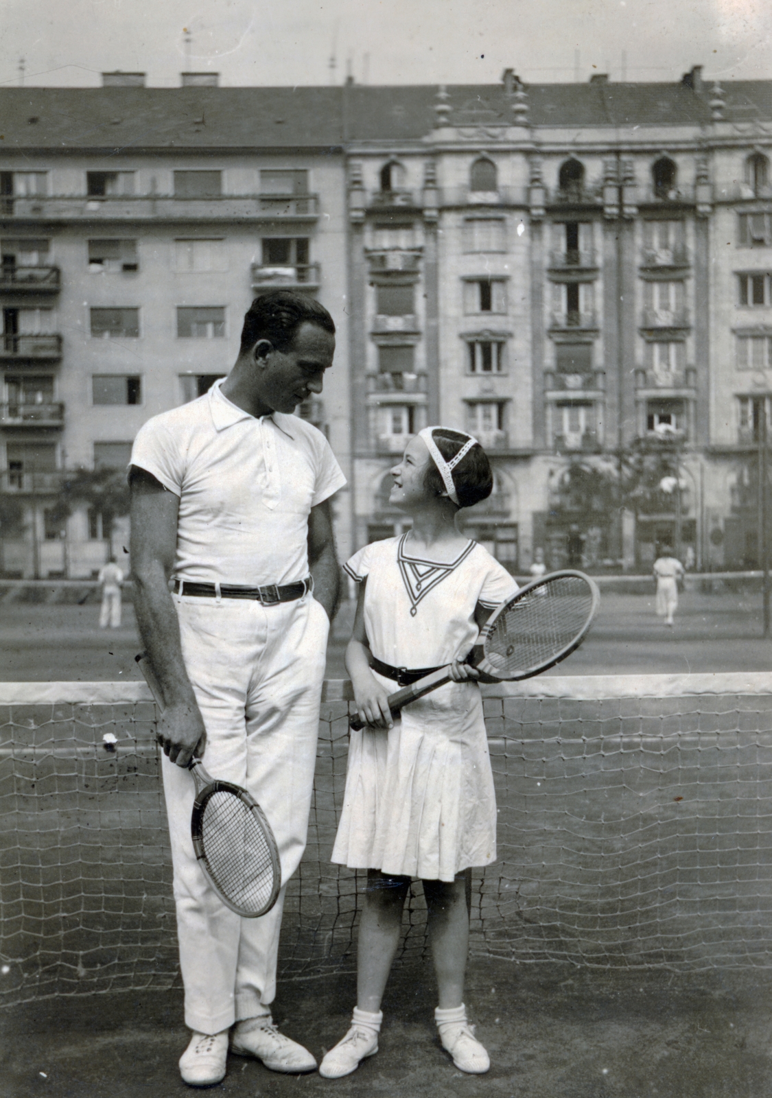Hungary, Budapest XIII., a Pozsonyi út - Balzac (Korall) utca - Hollán Ernő (Hollán) utca - Radnóti Miklós (Sziget) utcák által határolt Lipótvárosi Sporttelep (Pozsonyi út 27.) teniszpályái, háttérben a Pozsonyi út 24. és 26-28. számú ház., 1936, Barna Imre, Budapest, white dress, tennis rackets, Fortepan #150107