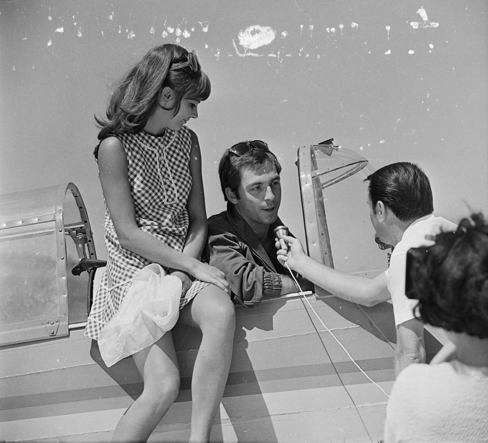 Magyarország, Almási Éva és Huszti Péter színművészek, Bokodi Béla riporter. Zlin Trener típusú repülőgép. A felvétel az Őrjárat az égen című tévésorozat forgatásán készült., 1969, MHSZ, színházművészet, híres ember, csehszlovák gyártmány, repülőgép, napszemüveg, mikrofon, repülőtér, Zlin-márka, színész, interjú, riporter, Fortepan #15402