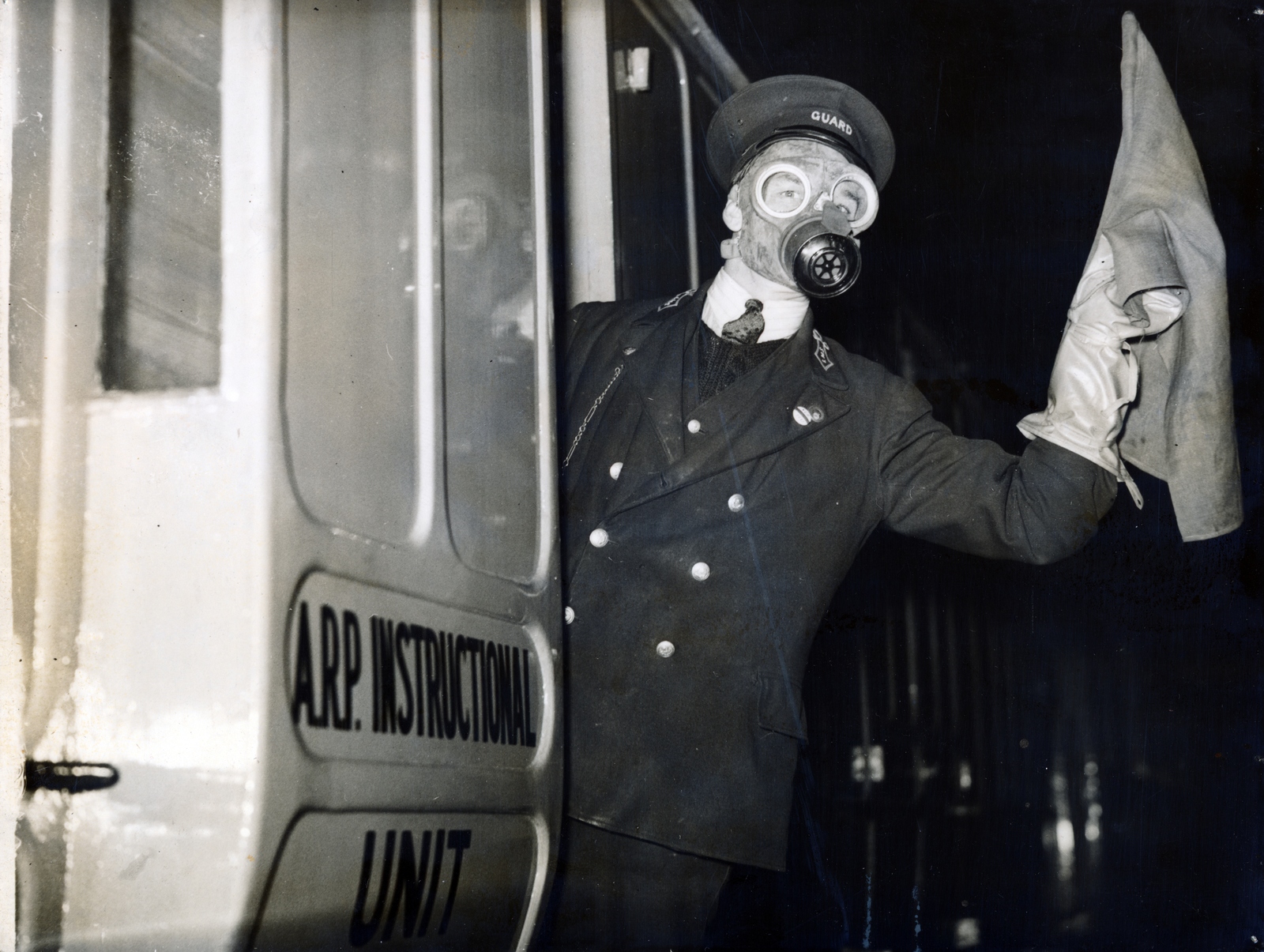 United Kingdom, London, Euston Station, légoltalmi gyakorlat (Air Raid Precautions). A vasúti személyzetei is kioktatják a légoltalmi teendőkre. „ Gázvonatokat" rendeztek be, melynek személyzete gázálarcban és gázvédő öltözetben végzi hivatalos teendőit. A vonat egyik kocsija teljes lég- és gázvédelmi felszerelést tartalmaz s ennek segítségével a személyzet gázsérülteknek elsősegélyt is nyújthat. Egy másik kocsit oktatóhelyiségnek rendeztek be, ahol szemléltető előadásokat tartanak., 1937, Reklámélet folyóirat, gas mask, Fortepan #156180