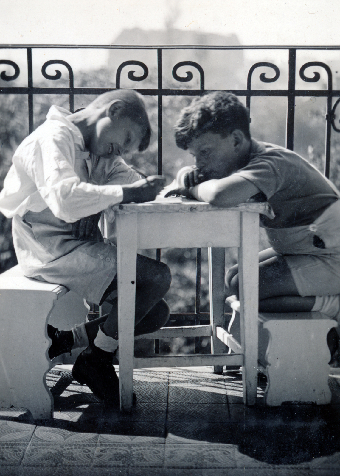 Hungary, Budapest XIV., Róna utca 121. körfolyosója, háttérben a Róna utca - Bosnyák utca sarkán álló épülettömb., 1934, Kinszki Imre, Budapest, footstool, boys, railing, writing, kitchen stool, child labour, Fortepan #157165