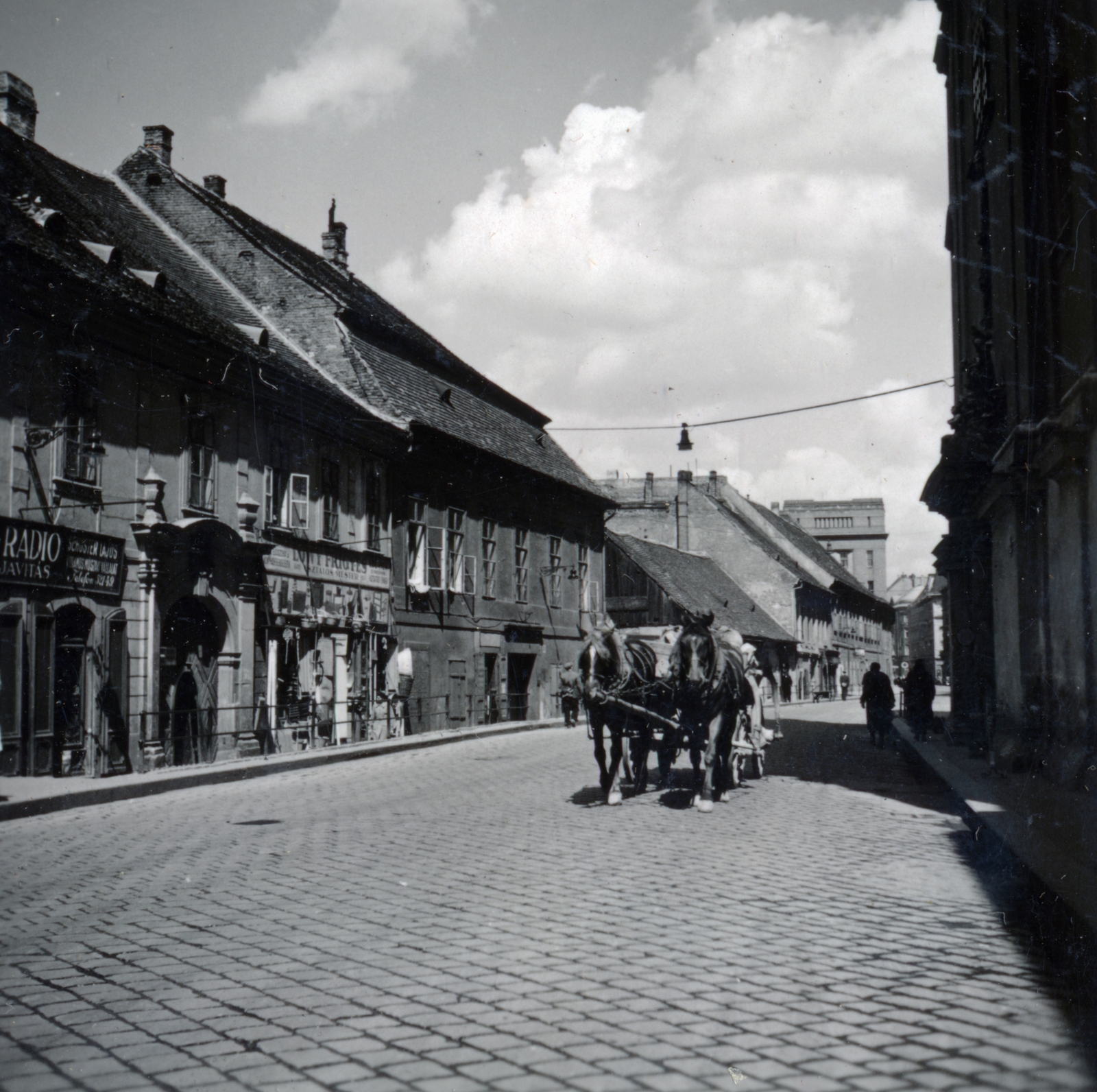 Hungary, Budapest I., Fő utca a Batthyány tér felöl a mai Nagy Imre tér felé nézve, ahol kimagaslik a Pestvidéki királyi törvényszék épülete. Jobbea a Szent Ferenc sebei templom., 1936, Boda Balázs, Budapest, street view, sign-board, photo aspect ratio: square, carpenter, cobblestones, Horse-drawn carriage, Fortepan #160477