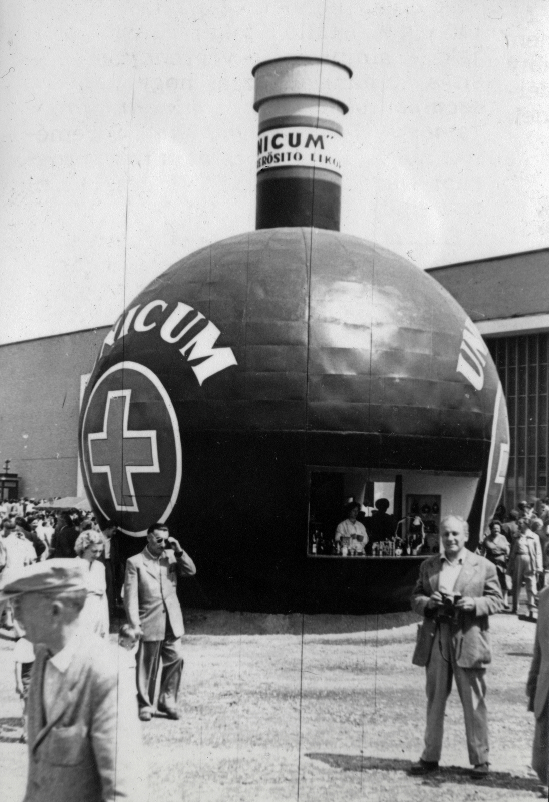 Magyarország, Városliget,Budapesti Ipari Vásár, Budapest XIV., az Unicum Likőrgyár üveg alakú pavilonja, háttérben az egykori Iparcsarnok helyén kialakított kiállítási pavilon, a Petőfi Csarnok., 1957, Márk Iván, Budapest, reklám, Fortepan #161378