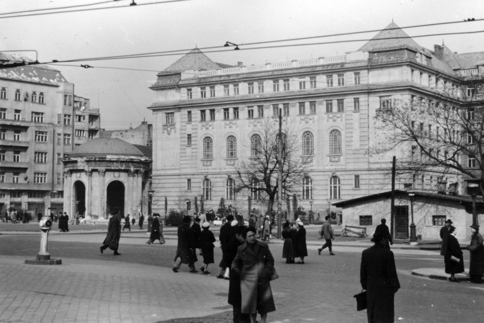 Magyarország, Budapest V., Március 15. tér, Erzsébet királyné emlékművének csarnoka, mögötte az ELTE Bölcsészkar (egykor és ma Piarista Gimnázium és Rendház) épülete., 1955, Gara család, Budapest, utcakép, járókelő, csibilámpa, épített örökség, eltűnt, Fortepan #162728