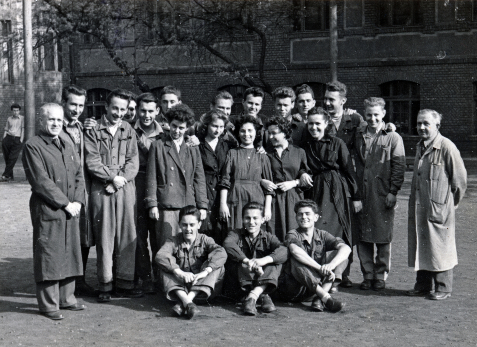 Hungary, Budapest IV., Görgey Artúr (Dózsa György) utca 26. A Landler Jenő Gépipari Technikum (később Újpesti Két Tanítási Nyelvű Műszaki Szakgimnázium és Szakközépiskola) udvara., 1957, Lichtmann Tibor, Budapest, overall, tableau, sitting on the ground, teacher, student, Fortepan #162851