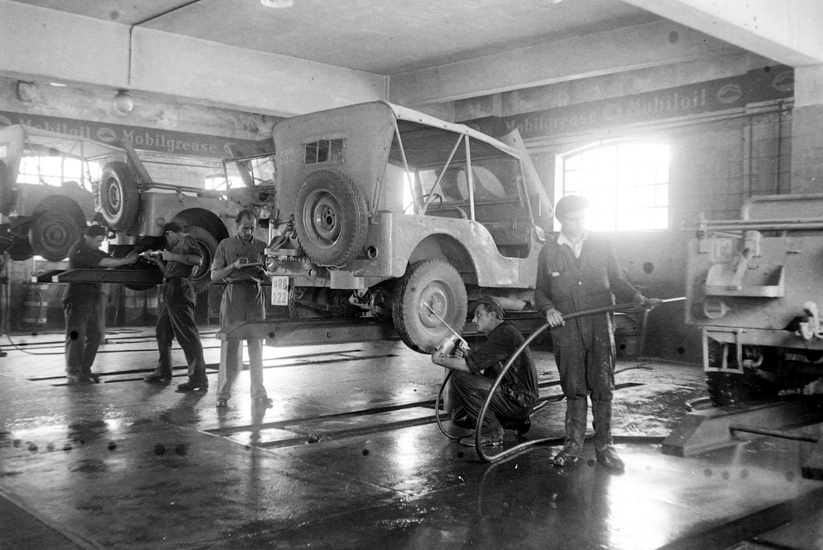 Hungary, Budapest XIII., Victor Hugo (Wahrmann Mór) utca 2-4. Az USA háborús készletéből kapott Willys Jeep rajkocsik a rendőrség gépjárműjavító műhelyében., 1948, Magyar Rendőr, american brand, worker, workshop, Jeep, Willys-brand, Budapest, Mobiloil-brand, mechanic, spare wheel, car repair, Fortepan #16449