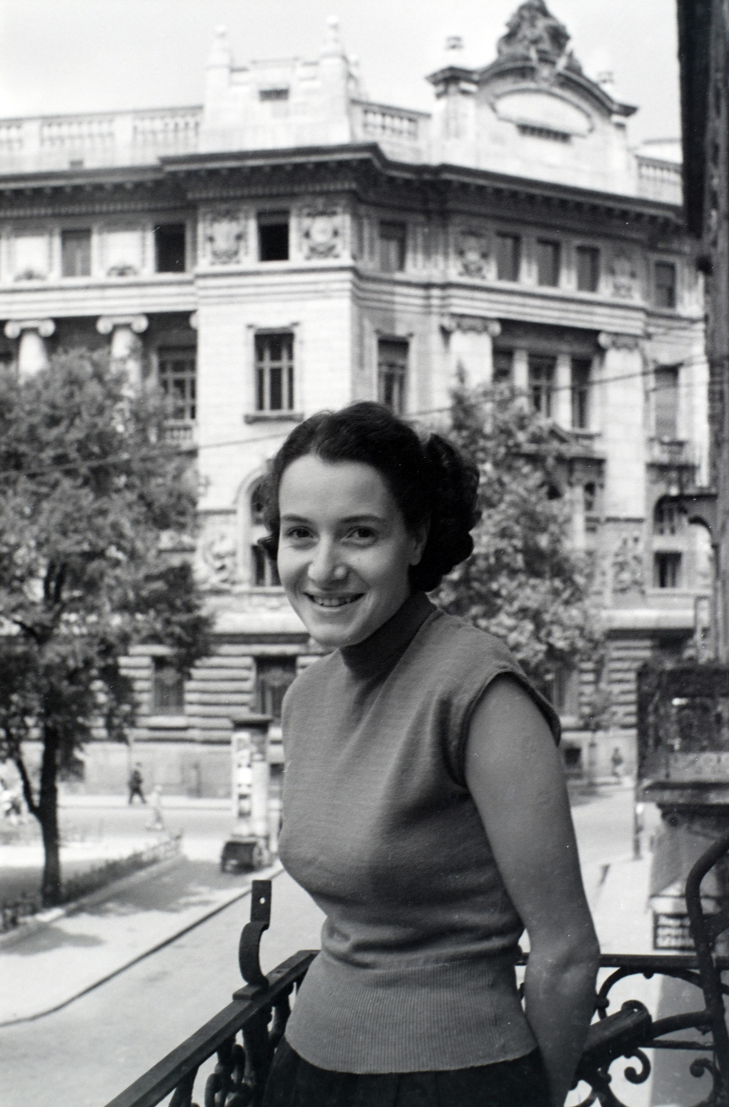 Magyarország, Budapest V., a Hercegprímás (Alpári Gyula) utca 19. számú ház I. emeleti erkélye, a háttérben a Magyar Nemzeti Bank épülete., 1958, Lőrinczi Ákos, Budapest, erkély, hajviselet, hölgy, mosoly, Fortepan #170581