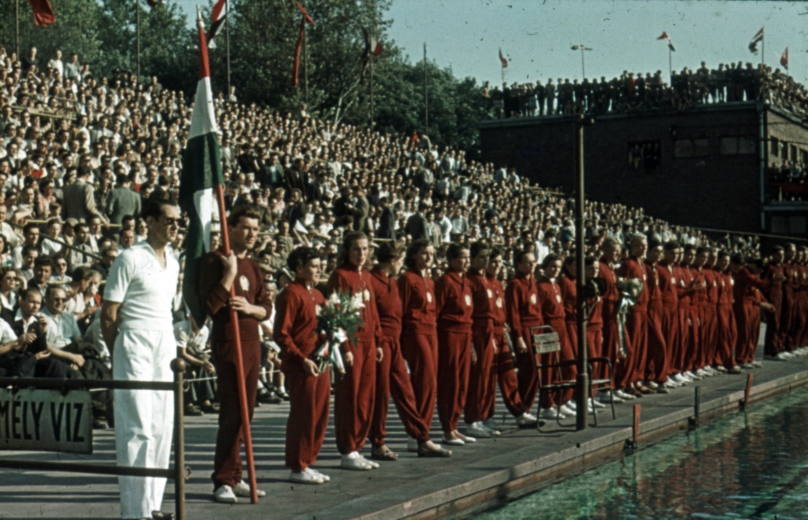 Hungary, Margit Islands, Budapest, Hajós Alfréd Nemzeti Sportuszoda, XII. Főiskolai Világbajnokság, a magyar csapatban virágcsokorral a kezében Székely Éva olimpiai bajnok., 1954, Sárosi Imre, colorful, sweater, auditorium, swimming pool, woman, team, olympic champion, Fortepan #170966
