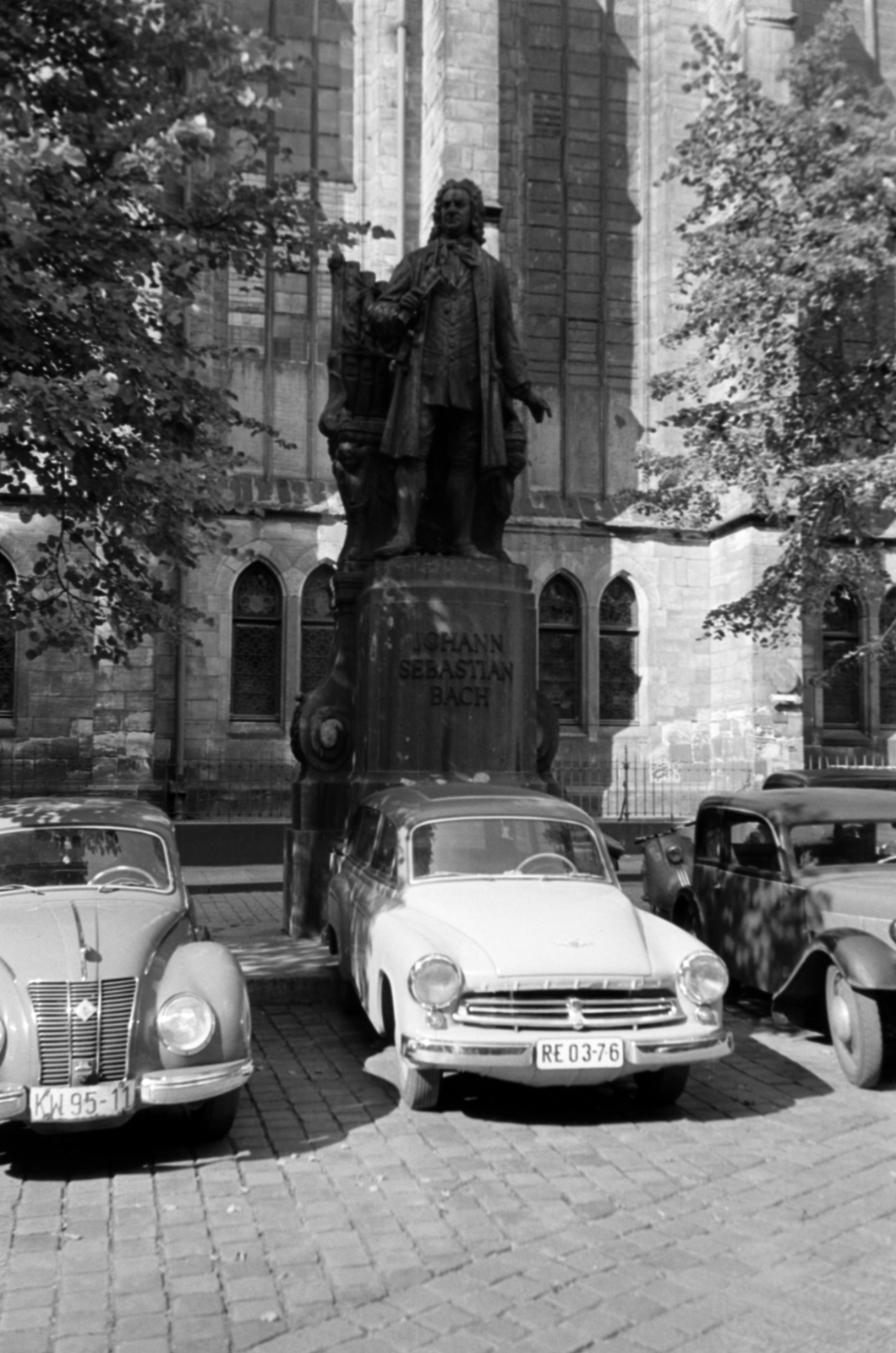 Németország, Lipcse, Thomaskirchhof, Bach-emlékmű, háttérben a Szent Tamás-templom (Thomaskirche)., 1957, Sattler Katalin, szobor, Wartburg-márka, NDK, rendszám, Fortepan #171176