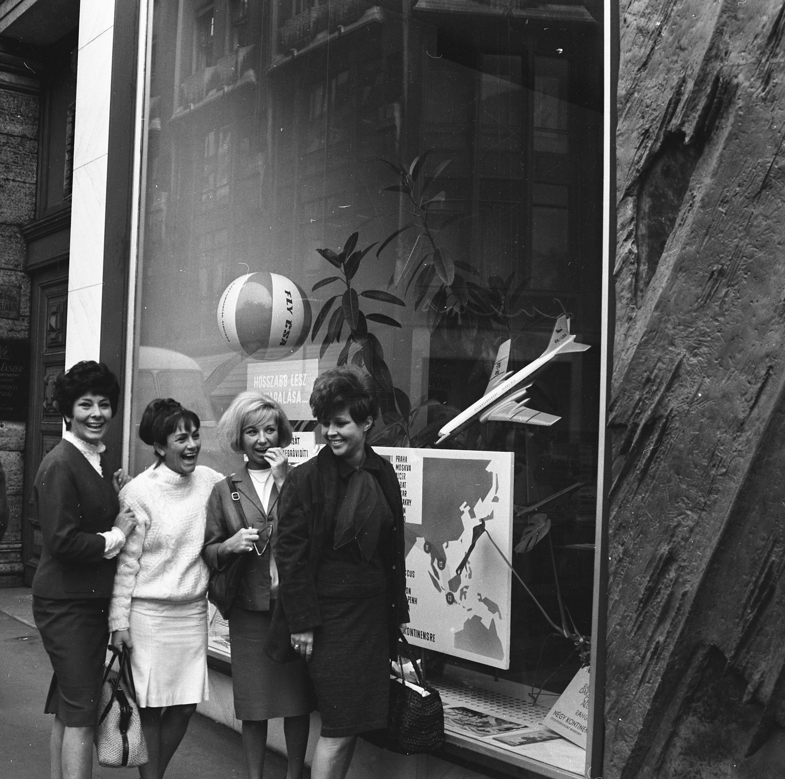 Magyarország, Budapest V., Vörösmarty tér 2., a csehszlovák légitársaság kirendeltségének kirakata előtt Faragó Vera, Vass Mari, Géczy Dorottya, Felföldi Anikó színművésznők a Leszállás Párizsban című színdarab szereplői., 1965, Kotnyek Antal, Budapest, Fortepan #173796