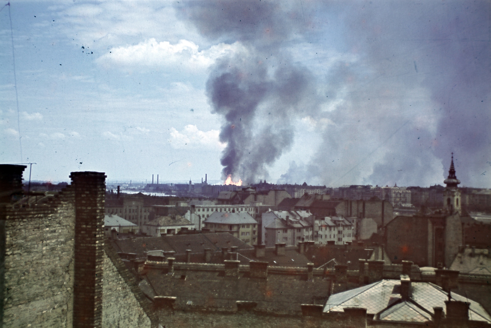 Magyarország, Budapest I., vízivárosi háztetők, kilátás a Szabó Ilonka (Ilona) utca irányából Újlipótváros felé, háttérben a lángoló Angyalföld az ipartelep szőnyegbombázása után., 1944, Zentai Dávid, Budapest, templomtorony, háztető, füst, Fortepan #174765
