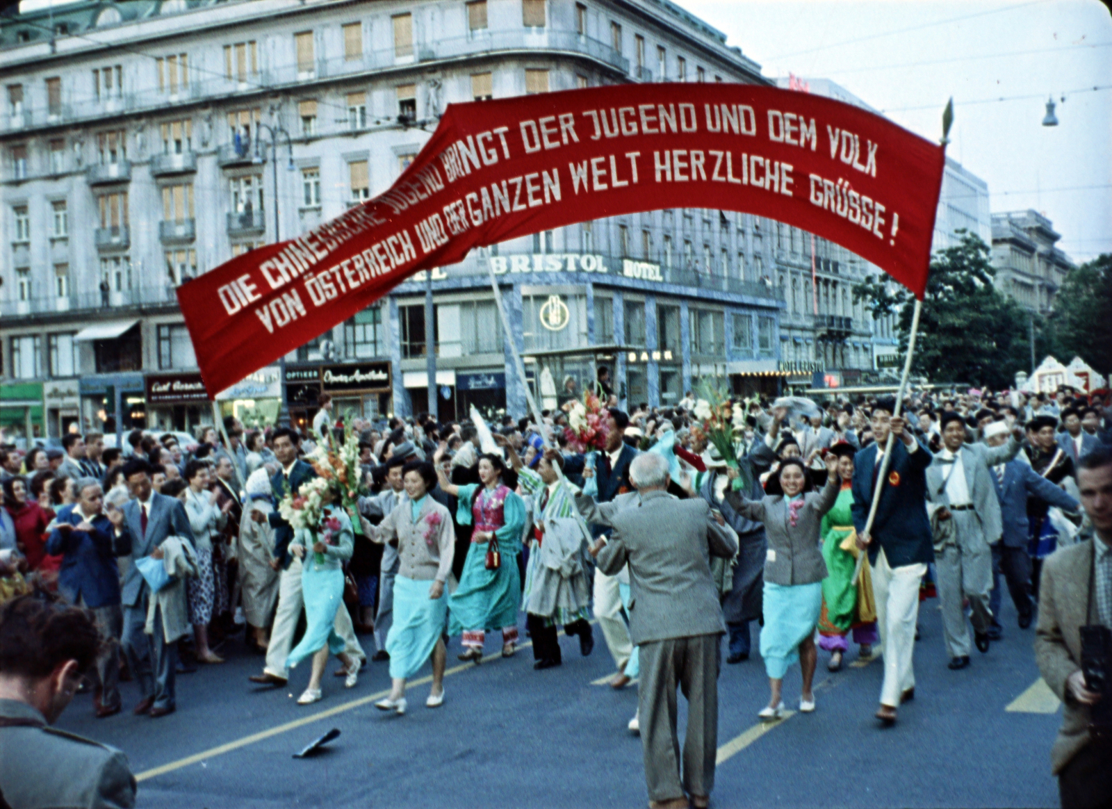 Austria, Vienna, a Kärntner Ring a Kärntner Strasse kereszteződésétől az Akademiestrasse felé nézve. A VII. VIT (Világifjúsági Találkozó) résztvevőinek felvonulása. Filmkocka a Bécsben találkoztunk című kisfilmből, rendező Kolonics Ilona, operatőrök Szabó Árpád és Fifilina József., 1959, Szabó Gábor, colorful, Fortepan #174798