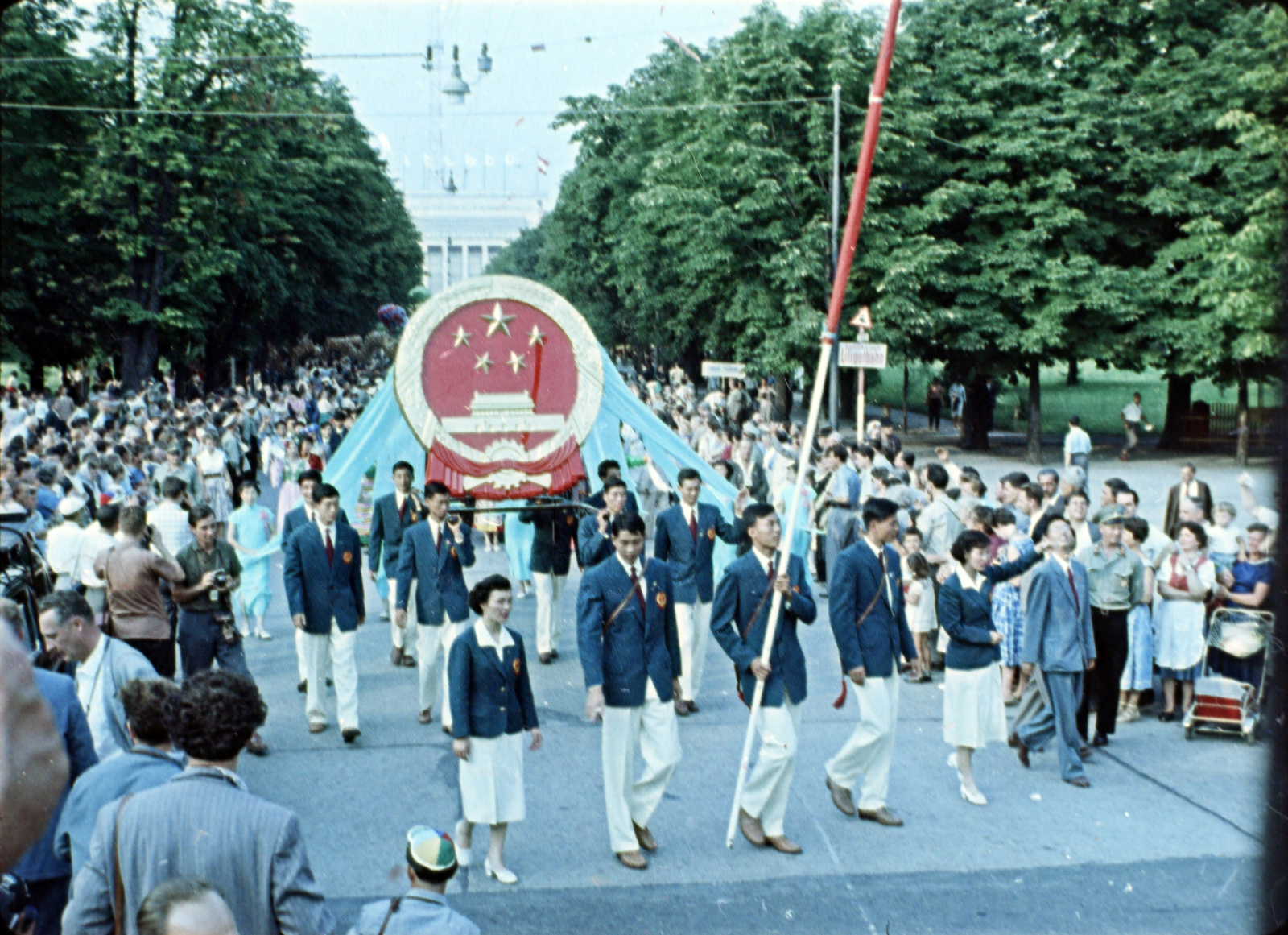Ausztria, Bécs, Kaiserallee a Rotundenplatz felé nézve, háttérben a Messe Wien (kiállítási és kongresszusi központ) a VII. VIT (Világifjúsági Találkozó) idején. Filmkocka a Bécsben találkoztunk című kisfilmből, rendező Kolonics Ilona, operatőrök Szabó Árpád és Fifilina József., 1959, Szabó Gábor, színes, Fortepan #174809