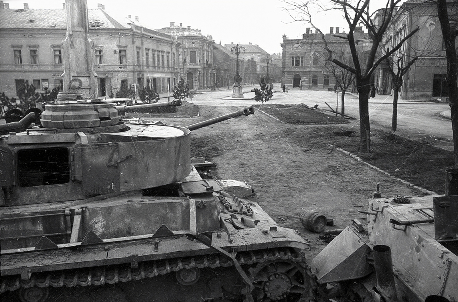 Hungary, Székesfehérvár, Zichy liget (Vilmos császár tér), szemben a Fő (Nádor) utca. A kép jobb szélén a Velence (előtte és később Magyar Király) szálló oldala, tőle balra a Vörösmarty Szinház épülete. A kép előterében bal oldalt a Szentháromság-szobor látható., 1945, Vörös Hadsereg, tank, wreck, Fortepan #175215