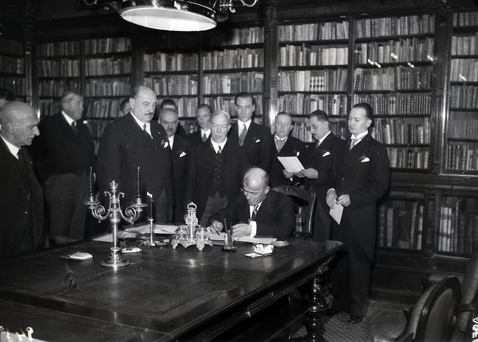 Hungary, Budapest VIII., a Magyar Nemzeti Múzeum Országos Széchényi Könyvtára, Apponyi-terem. Uuno Hannula finn kultuszminiszter aláírja a magyar-finn kultúregyezményt. Mellette balra Ormi Talas finn követ és Hóman Bálint kultuszminiszter, bal szélen Szily Kálmán államtitkár., 1937, Bojár Sándor, Budapest, signature, delegation, bookcase, Fortepan #177050