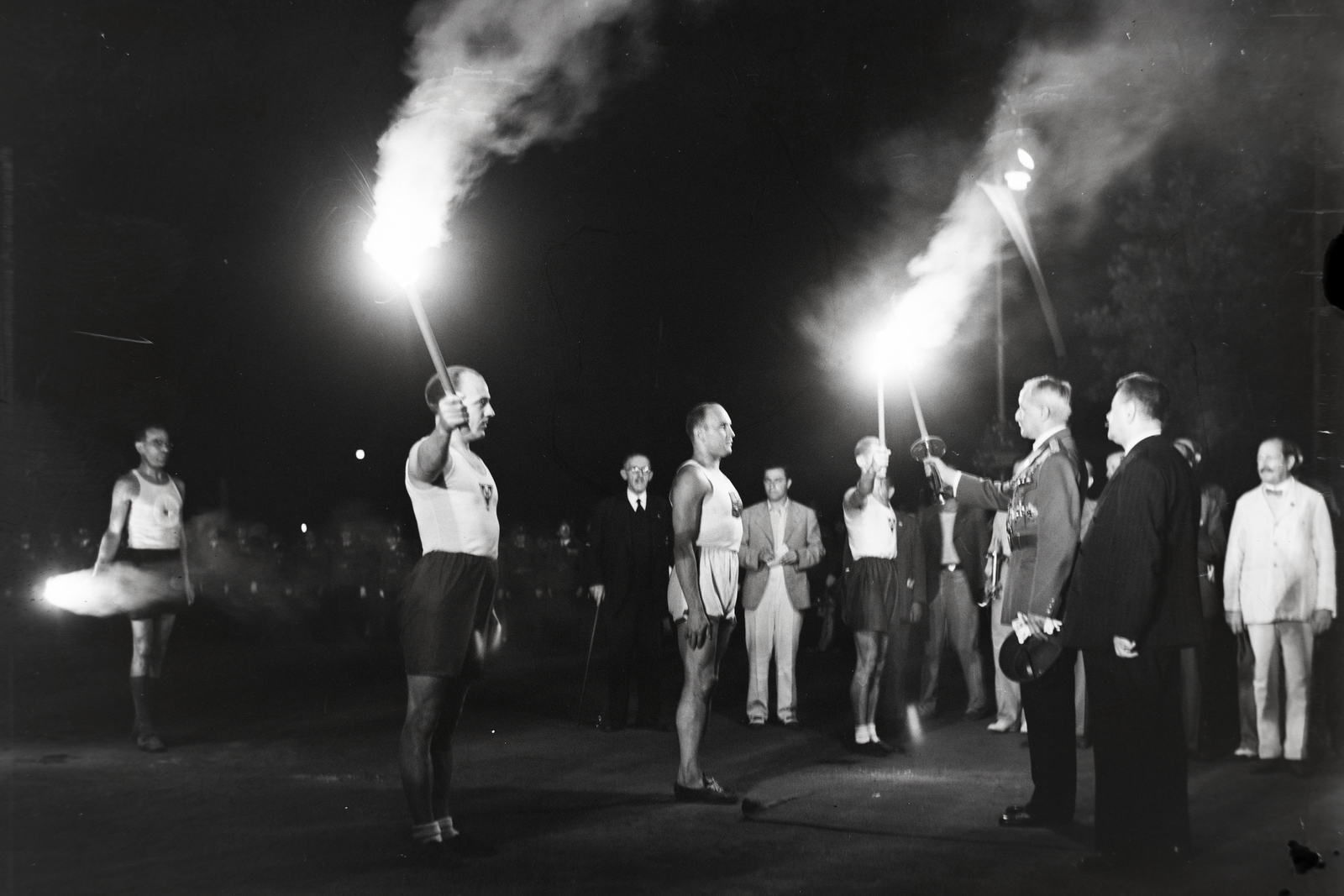 Hungary, Budapest XIV., Hősök tere, ünnepség a Hősök emlékkövénél a Berlinbe tartó olimpiai fáklya megérkezésekor. Középen fehér szerelésben Barsi László magyar futóbajnok, akitől gróf Takách-Tolvay József a MASz társelnöke vette át a fáklyát. Tőle jobbra sötét öltönyben Liber Endre alpolgármester. A felvétel 1936. július 28-án készült., 1936, Bojár Sándor, Budapest, olympic flame, Fortepan #177211