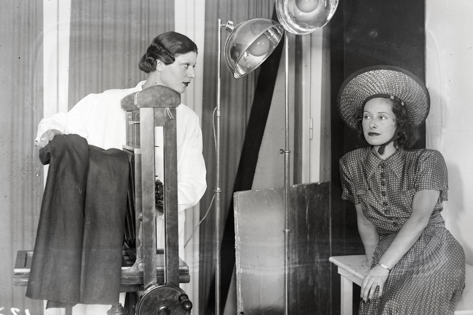 Hungary, Budapest VI., Akácfa utca 6., Rezsny Hedvig fényképész műterme. Fehér köpenyben Márkus Margit színésznő tanulja a fényképészmesterséget, portrét készít Muráti Lili színművésznőről., 1938, Bojár Sándor, Budapest, studio camera, photography, portrait, photographer, camera, staged, Fortepan #177349