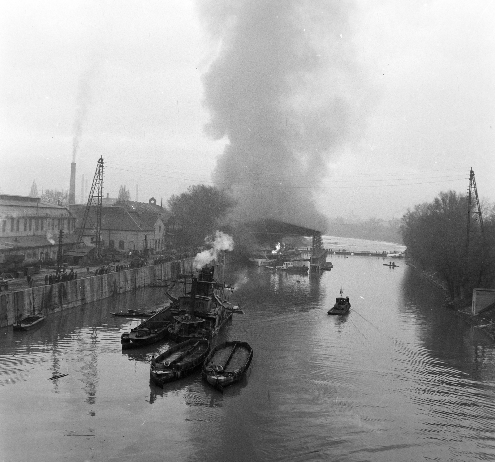 Hungary, Óbuda, Budapest III., Óbudai Hajógyár, a Hajógyári-öböl az Árpád hídról nézve. A hajóvédő csarnokban egy átadás előtt álló gőzhajón a keletkezett tüzet oltják. Újjáépítés után ez lett a SZOT Budapest üdülőhajó., 1959, Bojár Sándor, Budapest, Fortepan #178884