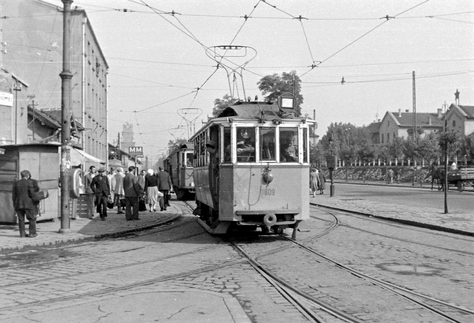 Magyarország, Budapest VIII., Orczy tér a Fiumei út felé nézve, jobbra a Józsefvárosi pályaudvar, a háttérben az OTI épület (azóta lebontott) tornya., 1953, Magyar Rendőr, közlekedés, lovaskocsi, utcakép, életkép, villamos, villamosmegálló, Budapest, vörös csillag, Fortepan #17960