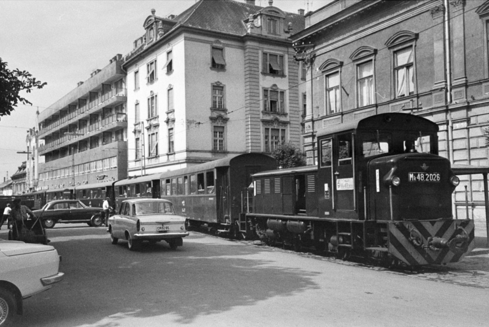 Magyarország, Nyíregyháza, Kossuth tér, balra a Zrínyi Ilona utca, jobbra a Bethlen Gábor utca torkolata. Az NyVKV (Nyíregyházavidéki Kisvasutak) szerelvénye a villamossal közös pályaszakaszon., 1968, Bojár Sándor, dízelmozdony, MÁV MK48 sorozat, MÁV Bax, Fortepan #180008