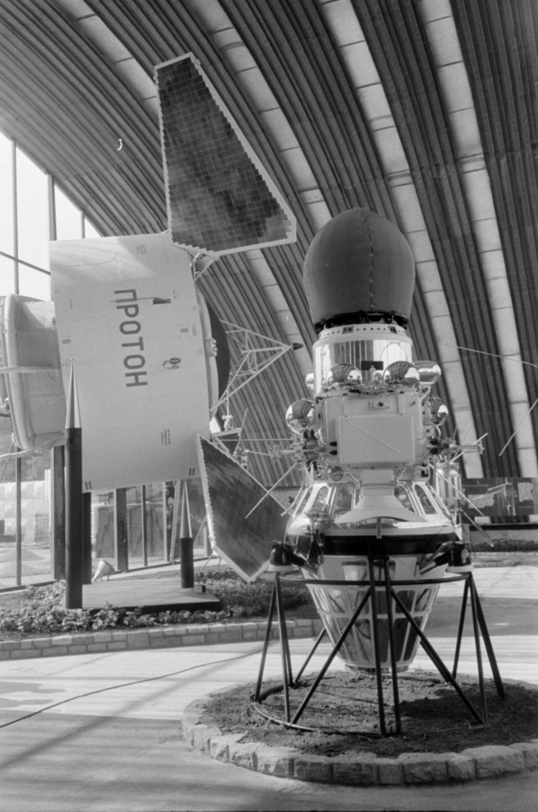 Magyarország, Városliget, Budapest XIV., a BNV területe, a Szovjet tudomány és technika 50 éve jubileumi kiállítása 1967. szeptember 1-24. A Luna–9 modellje, az űrszonda tetején a leszálló modullal. Háttérben a Proton-1 tudományos műhold, űrlaboratórium., 1967, Bojár Sándor, Budapest, űrhajó, makett, Fortepan #180227