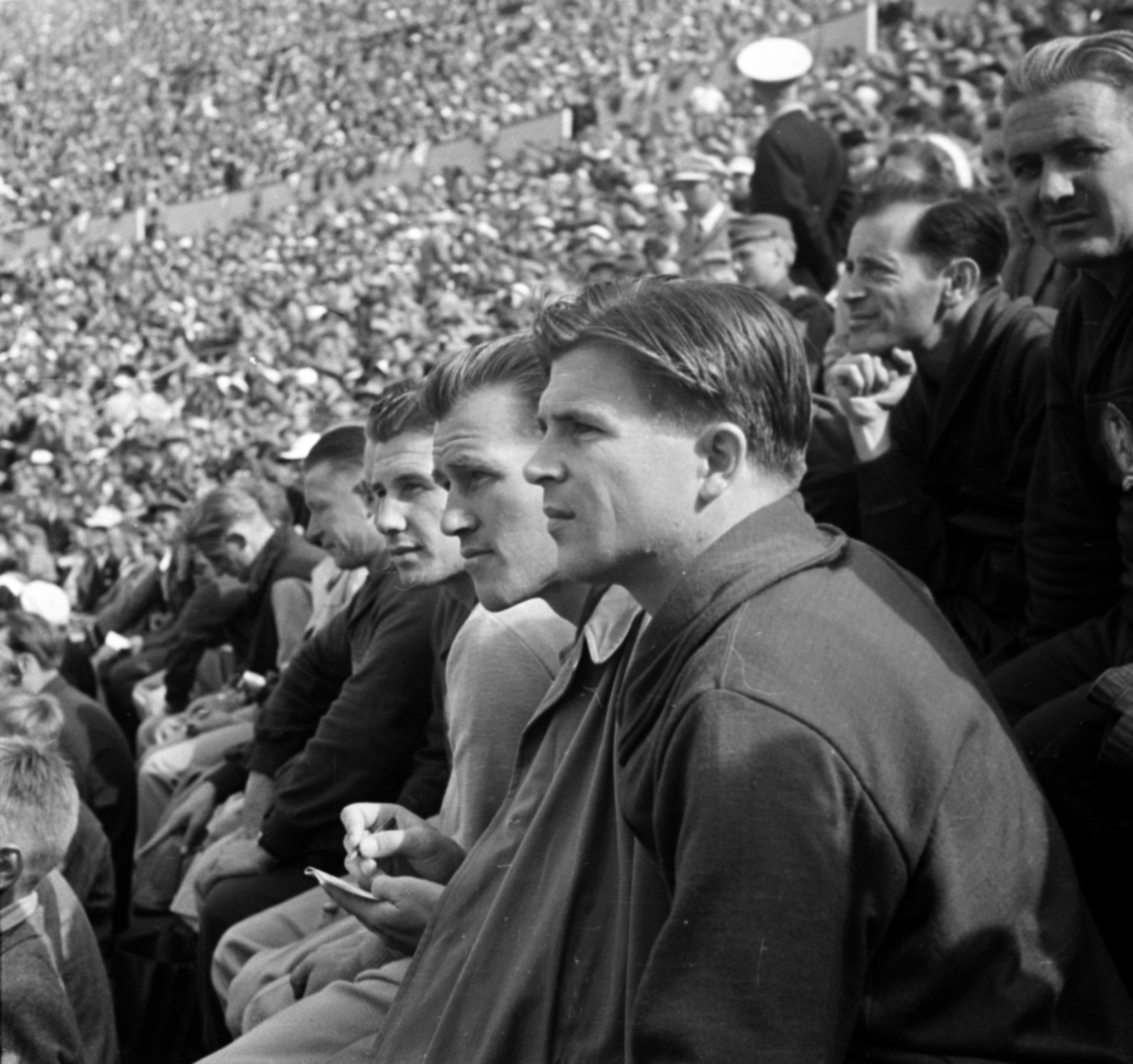 Finland, Helsinki, XV. nyári olimpiai játékok, Olimpiai Stadion. Olimpiai bajnok labdarúgóink a lelátón, előtérben Puskás Ferenc, majd tőle távolodva Börzsei János, Zakariás József, Kalmár Jenő edző és Lóránt Gyula. Mögöttük állát támasztva Zsolt István játékvezető., 1952, Bojár Sándor, Olympics, photo aspect ratio: square, audience, celebrity, olympic champion, football, Fortepan #180400