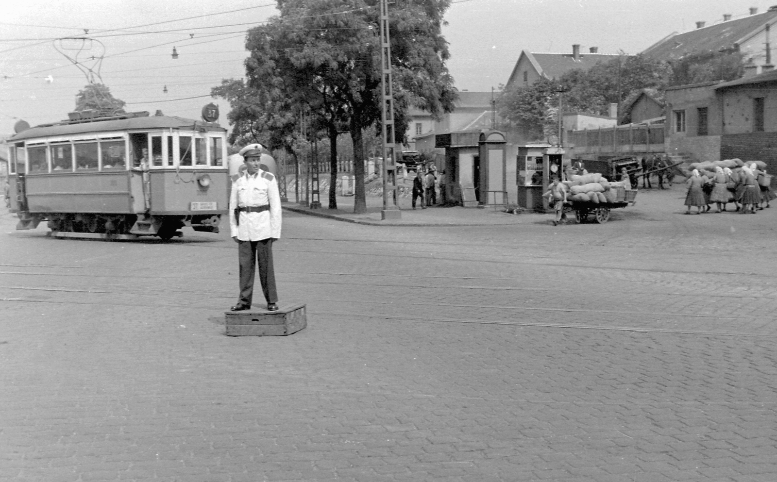 Magyarország, Budapest VIII., Orczy tér a Fiumei út felé nézve, jobbra a Józsefvárosi pályaudvar., 1954, Magyar Rendőr, lovaskocsi, utcakép, életkép, rendőr, villamos, fogat, telefonfülke, benzinkút, kockakő, kézikocsi, rendőrdobogó, Budapest, viszonylatszám, Fortepan #18095