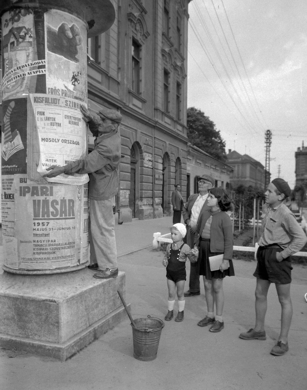 Hungary, Zalaegerszeg, Mindszenty József (Kovács Károly) tér a Nagytemplom előtt, balra a Kazinczy (Marx) tér 1. számú ház oldalhomlokzata., 1957, Kotnyek Antal, ad pillar, kids, curiosity, sticker, Fortepan #18220