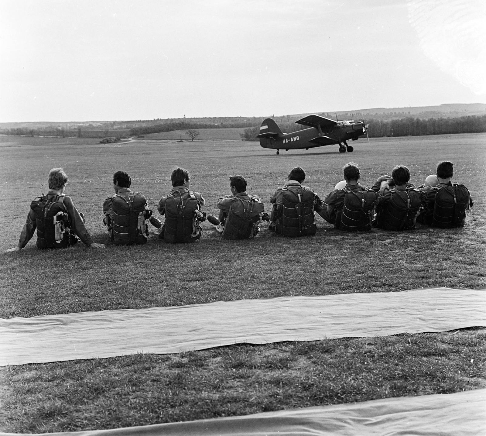 Magyarország, Gödöllő, repülőtér, ejtőernyősök, háttérben egy Antonov An-2 típusú repülőgép., 1968, MHSZ, háttal, libasor, nagyság szerint, ejtőernyős, biplán, Fortepan #185893